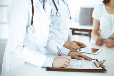 İş yerindeki bilinmeyen kadın doktorlar hastalara danışıyor. Tıbbi belge ya da reçete dolduran kadın doktorlar, yakın çekim. Sağlık hizmeti kavramı