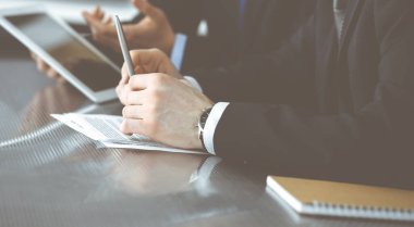 Bilinmeyen işadamları tablet bilgisayar kullanıyor ve modern ofisteki cam masada birlikte çalışıyorlar. Yakın plan. Takım çalışması ve ortaklık kavramı