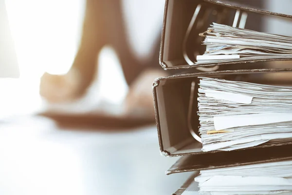 Binders with papers are waiting to be processed by business woman or bookkeeper working at the desk in office back in blur. Audit and tax concept — Stock Photo, Image