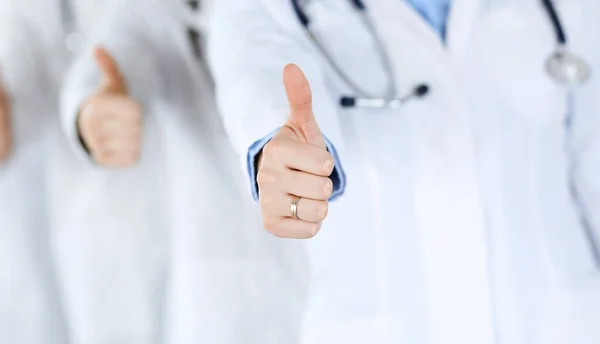 Groupe de médecins modernes debout en équipe avec les pouces vers le haut dans le bureau de l'hôpital. Aide médicale, assurance dans les soins de santé, meilleur traitement de la maladie et concept de médecine — Photo