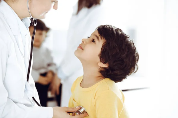 Medico-donna che esamina una paziente infantile mediante stetoscopio. Carino il ragazzo arabo all'appuntamento dal medico. Medicina concetto di aiuto — Foto Stock