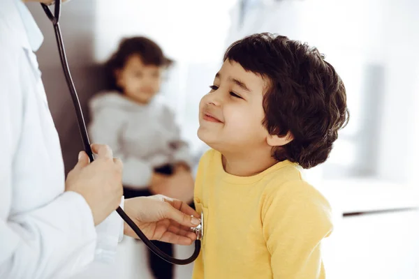 Mujer-médico examinando a un niño paciente por estetoscopio. Lindo chico árabe en la cita con el médico. Medicina ayuda concepto — Foto de Stock