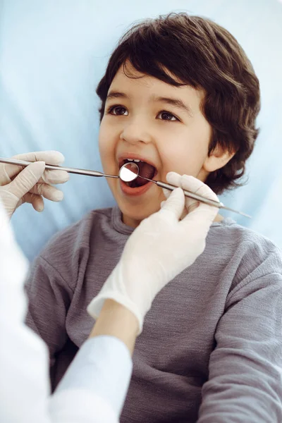 Pequeño chico árabe sentado en la silla dental con la boca abierta durante la revisión oral con el médico dentista. Concepto de estomatología — Foto de Stock