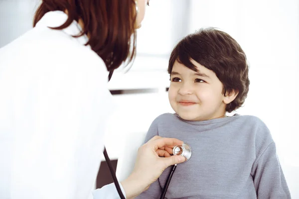 Doctor-woman examining a child patient by stethoscope. Cute arab boy at physician appointment. Medicine concept — Stock Photo, Image