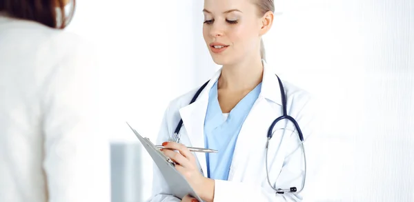 Femme médecin consulte sa patiente tout en utilisant presse-papiers et les antécédents de médicaments. Concept de médecine — Photo