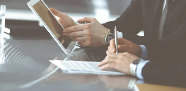 Empresarios desconocidos que usan tableta y trabajan juntos en el escritorio de cristal en la oficina moderna, de cerca. Trabajo en equipo y concepto de asociación —  Fotos de Stock