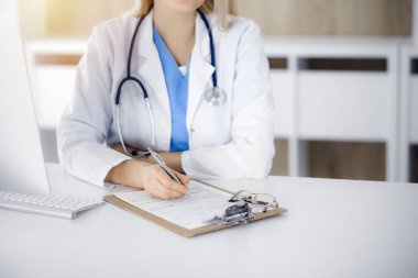 Sunny Kliniği 'nde tıbbi geçmişi dolduran kimliği belirsiz kadın doktor, yakın plan.