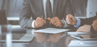 Bilinmeyen iş adamları modern ofiste birlikte çalışıyorlar, yakın plan. İş adamı ve kadın iş arkadaşları veya avukatlarıyla pazarlıkta sözleşmeyi tartışıyor