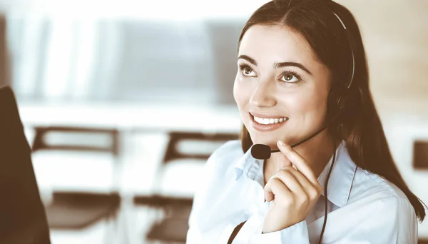 Brunette representante de atendimento ao cliente do sexo feminino em um fone de ouvido está consultando clientes on-line. Call center e conceito de pessoas de negócios — Fotografia de Stock