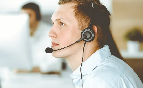 Group of diverse operators at work in call center. Businessman sitting n headset at customer service office. Business concept —  Fotos de Stock