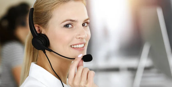 Mulher de negócios loira usando fone de ouvido para comunicação e consultoria de pessoas no escritório ensolarado. Centro de atendimento — Fotografia de Stock