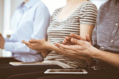 İş adamları toplantı ya da konferansta el çırpıyor. Modern beyaz ofisteki bir grup tanınmayan iş adamı ve kadın. Başarı takım çalışması, kurumsal koçluk ve alkış konsepti