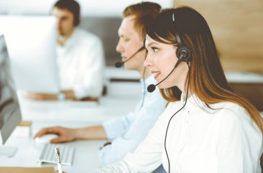 Çağrı merkezinde çalışan çeşitli operatörler. Güzel Asyalı kadın müşteri hizmetleri ofisinde kulaklık takıyor. İş konsepti