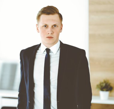 Ofisteki kameraya bakıp duran neşeli iş adamı. Genç ve başarılı girişimcinin vesikalığı