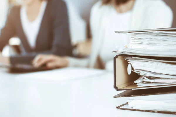 Binders with papers are waiting to be processed by business woman or bookkeeper working at the desk in office back in blur. Audit and tax concept — Stock Photo, Image