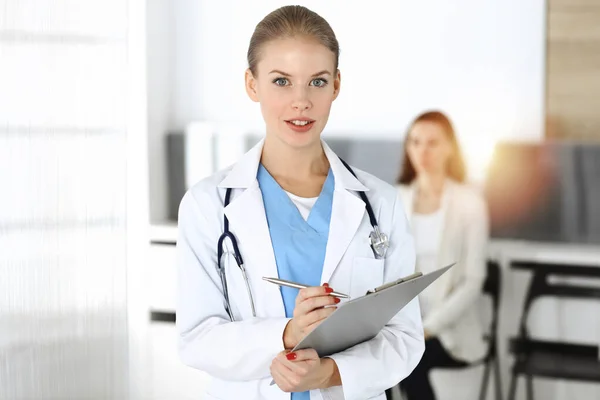 Donna - il medico sta usando appunti per riempire la cartella clinica soleggiata sullo sfondo del paziente — Foto Stock