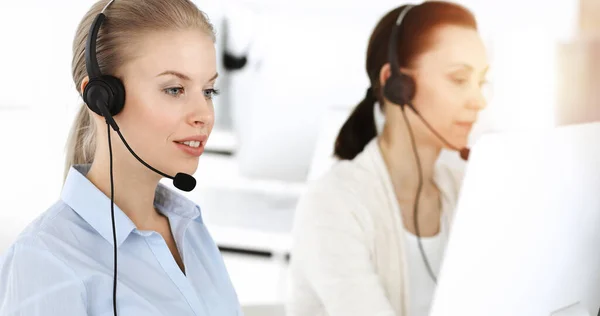 Mujer rubia trabajando en un centro de llamadas soleado. Grupo de personas diversas que trabajan como ocupación de servicio al cliente. Concepto empresarial — Foto de Stock