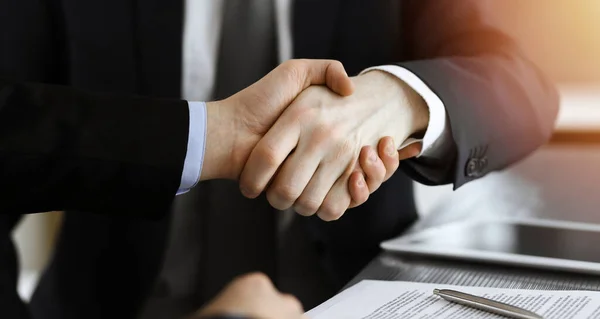 Zakenman schudt handen met zijn collega boven het glazen bureau in zonnig modern kantoor, close-up. Onbekende zakenmensen bij vergadering — Stockfoto