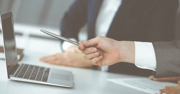 Empresarios y mujeres desconocidos sentados, usando computadora portátil y discutiendo preguntas en la reunión en la oficina moderna, primer plano —  Fotos de Stock