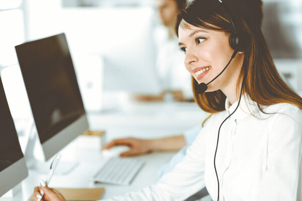 Group of diverse operators at work in call center. Beautiful asian woman sitting in headset at customer service office. Business concept