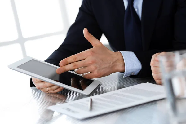 Business people using tablet computer while working together in modern office. Unknown businessman with colleague at workplace. Teamwork and partnership concept Royalty Free Stock Photos