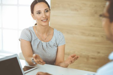 İş adamı ve İspanyol iş kadını güneşli ofiste bilgisayarla çalışıyor. Çeşitli insanlardan oluşan bir grup