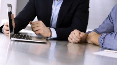 Modern ofiste birlikte çalışırken dizüstü bilgisayarı kullanan iş adamları. İş yerinde iş arkadaşı olan tanınmamış bir iş adamı ya da erkek girişimci. Takım çalışması ve ortaklık kavramı