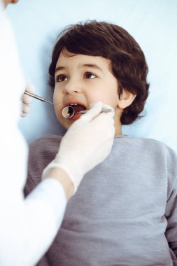 Küçük Arap çocuk dişçi doktoruna sözlü muayene sırasında ağzı açık bir şekilde dişçi koltuğunda oturuyor. Stomatoloji kavramı