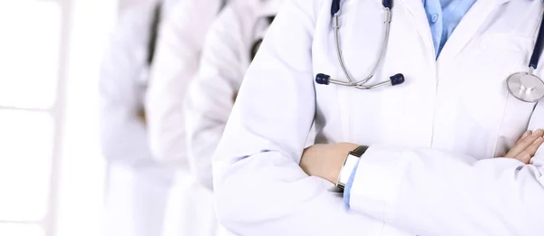 Grupo de médicos modernos de pie como un equipo con los brazos cruzados en la oficina del hospital. Ayuda médica, seguro de salud, mejor tratamiento de enfermedades y concepto de medicina — Foto de Stock