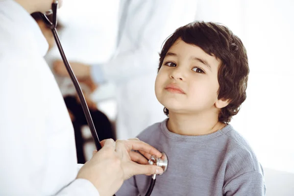 Docteur-femme examinant un enfant patient par stéthoscope. Joli garçon arabe et son frère au rendez-vous chez le médecin. Concept de médecine — Photo