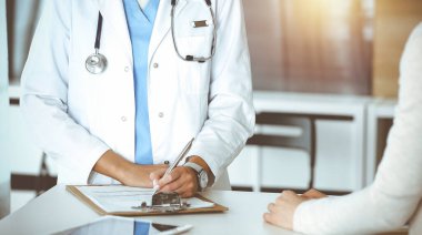 Sunny Hastanesi 'nde bilinmeyen bir kadın doktor ve hasta var. Doktor ilaç geçmişi kayıtlarını ve sınav sonuçlarını kontrol ederken pano kullanıyor, yakın plan.