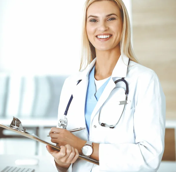 La mujer doctora en el trabajo en el hospital controla los historiales de medicamentos y los resultados del examen mientras usa el portapapeles. Concepto de medicina y salud — Foto de Stock