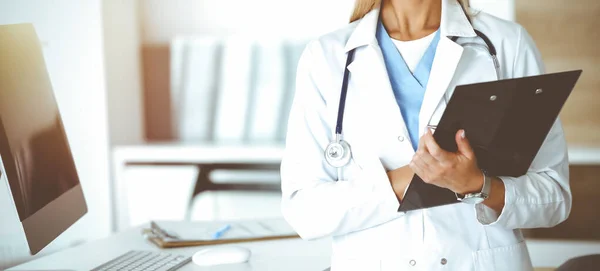 Onbekende vrouw-dokter op het werk in een zonnige kliniek. Vrouwelijke arts controleert de geschiedenis van medicatie, close-up. Geneesmiddelenconcept — Stockfoto