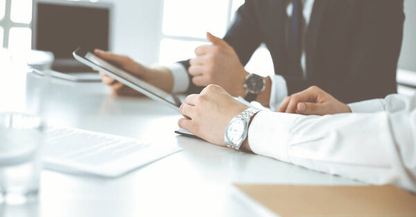 Неизвестные бизнесмены используют планшетный компьютер в современном офисе. Бизнесмен или предприниматель работает со своим коллегой за столом