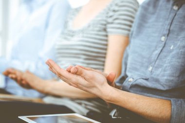 İş adamları toplantı ya da konferansta el çırpıyor. Modern beyaz ofisteki bir grup tanınmayan iş adamı ve kadın. Başarı takım çalışması, kurumsal koçluk ve alkış konsepti