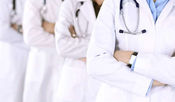 En grupp moderna läkare som står som ett team med armarna korsade på sjukhusets kontor. Medicinsk hjälp, sjukförsäkring, bästa sjukdomsbehandling och medicinska koncept — Stockfoto