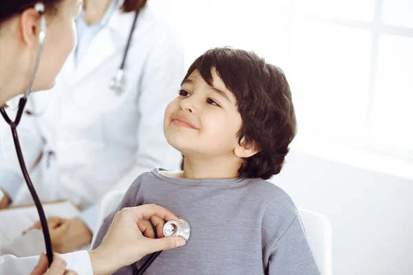 Médico-mujer examinando a un niño paciente por estetoscopio. Lindo chico árabe en la cita con el médico. Concepto de medicina — Foto de Stock