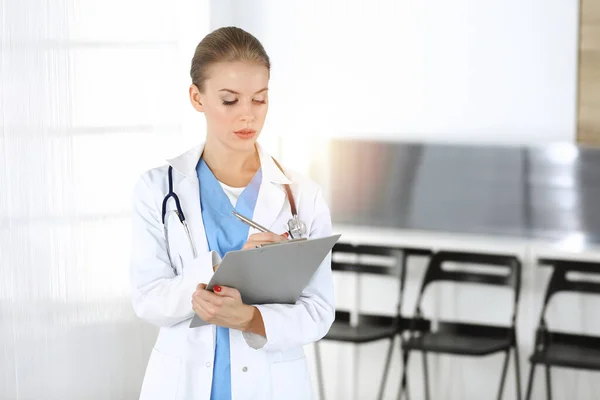 Mulher - médico está usando prancheta para encher registro de histórico de medicação na clínica. Conceito de medicina — Fotografia de Stock