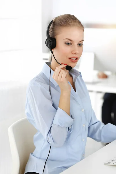 Mujer rubia trabajando en un centro de llamadas soleado. Grupo de personas diversas que trabajan como ocupación de servicio al cliente. Concepto empresarial — Foto de Stock