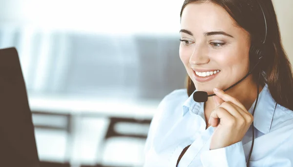 Morena representante de servicio al cliente femenino en un auricular está consultando a los clientes en línea. Centro de llamadas y concepto de gente de negocios — Foto de Stock