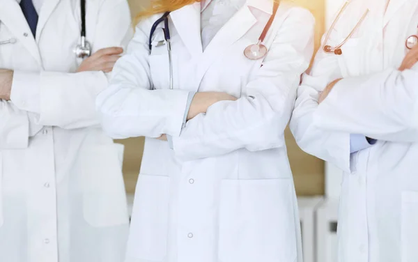 Gruppen av moderna läkare står som ett team med armarna korsade på sjukhus kontor, närbild. Medicinsk hjälp, sjukförsäkring, bästa behandlings- och medicinkoncept — Stockfoto