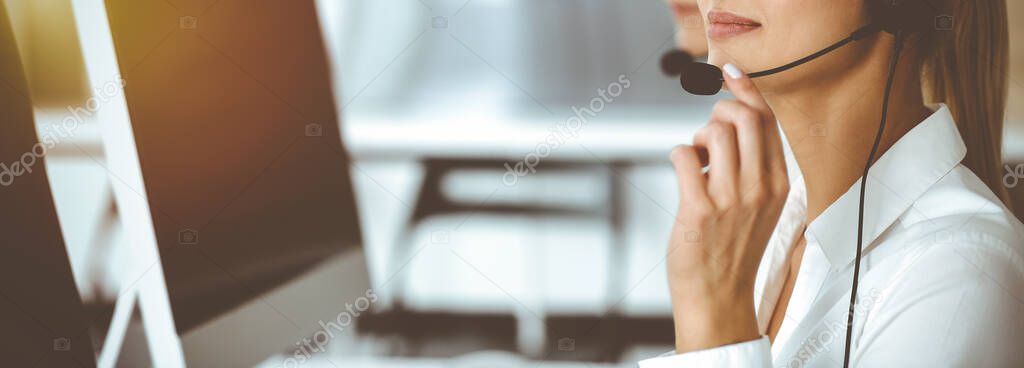 Unknown female customer service representative iconsulting clients online using headset.close-up. Sunny Call center