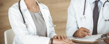 İki bilinmeyen doktor hastane ofisinde masa başında otururken tedavi sorunlarını tartışıyor, yakın plan. Tıptaki veriler