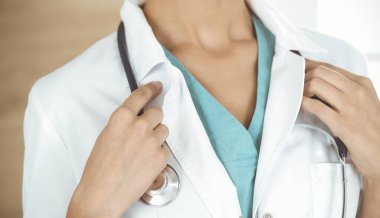 Klinikte steteskopla duran kimliği belirsiz kadın doktor, yakın plan. Tıp konsepti