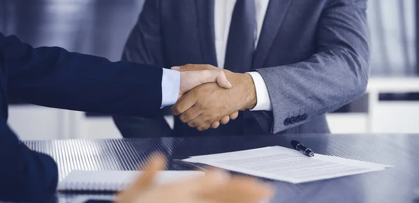 Unknown business people are shaking hands after contract signing in modern office, close-up. Handshake as successful negotiation ending