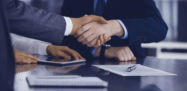 Handshake as successful negotiation ending, close-up. Unknown business people shaking hands after contract signing in modern office