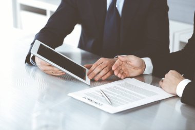 İş adamları modern ofiste çalışırken tablet bilgisayar kullanıyorlar. İş yerinde iş arkadaşı olan bilinmeyen bir iş adamı. Takım çalışması ve ortaklık kavramı
