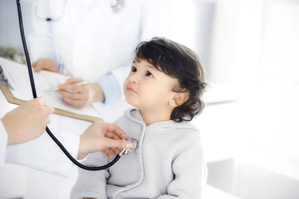 Mujer-médico examinando a un niño paciente por estetoscopio. Lindo niño árabe en la cita con el médico. Concepto de medicina —  Fotos de Stock