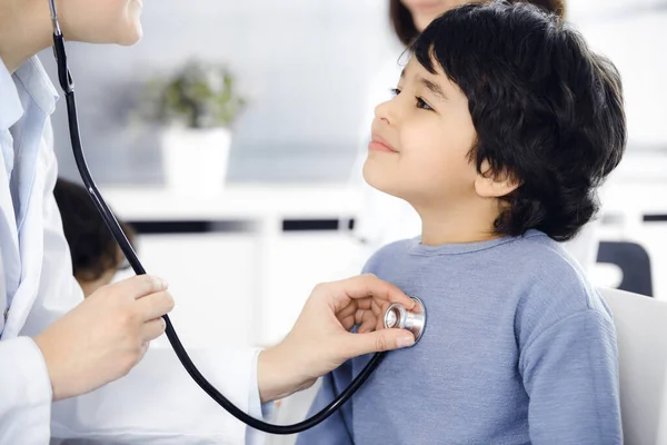 Médico-mujer examinando a un niño paciente por estetoscopio. Lindo chico árabe en la cita con el médico. Concepto de medicina —  Fotos de Stock