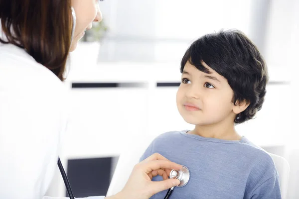 Orvos-nő sztetoszkóppal vizsgál meg egy gyermekbeteget. Aranyos arab fiú az orvosnál. Orvosi fogalom — Stock Fotó